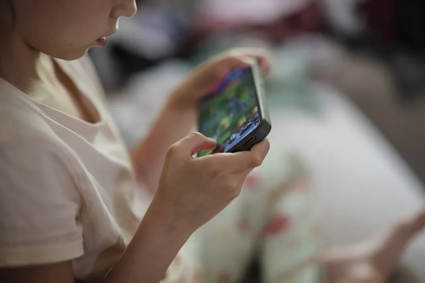 Close-up of a child using a smartphone to play games at home