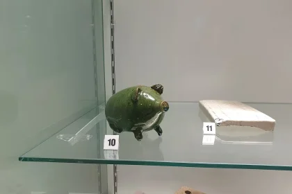 A traditional piggy bank displayed in a museum, a symbol of basic saving habits